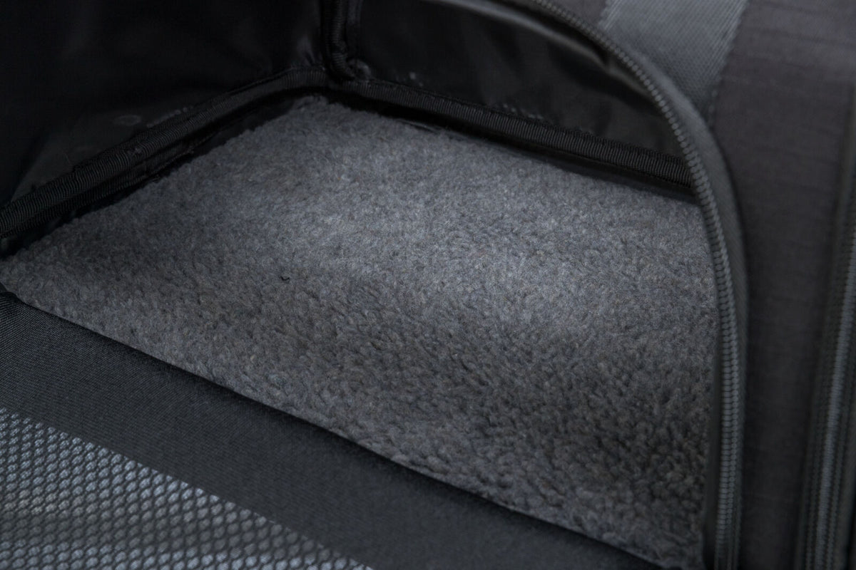 Innenansicht einer schwarzen Tasche mit grauem, texturiertem Boden und Reißverschluss an der Seite.
