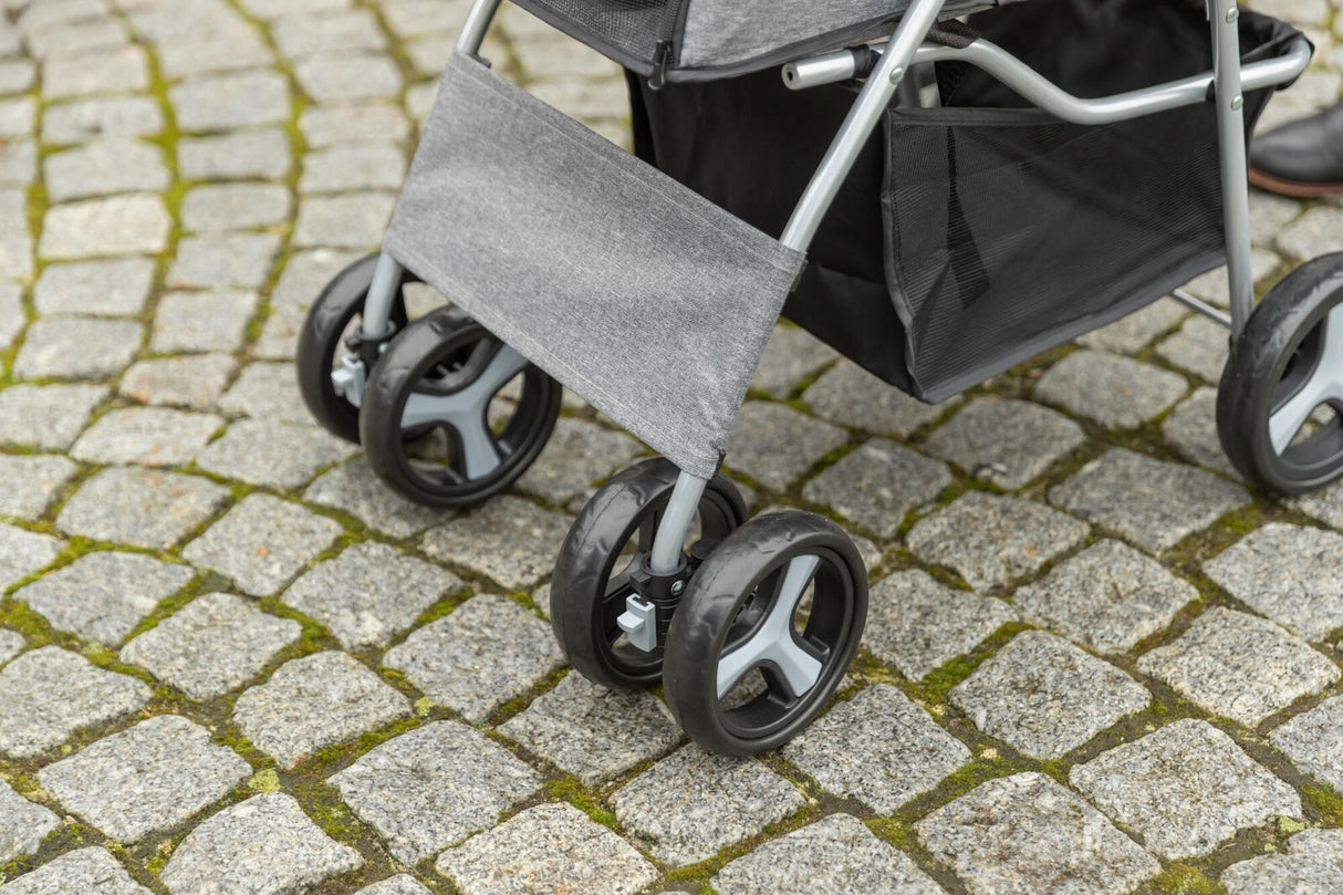 Grauer Kinderwagen mit vier Rädern steht auf einem mit Moos bewachsenen Kopfsteinpflasterweg.