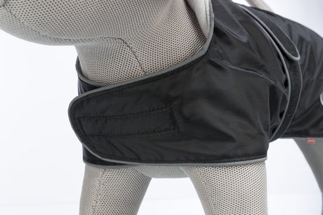 Graues Modell mit schwarzem Hundemantel und Klettverschluss auf weißem Hintergrund.