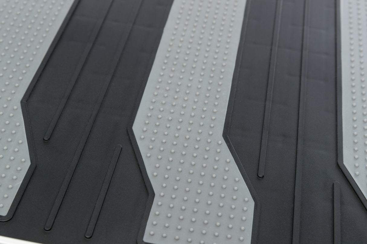 Schwarze und graue Oberfläche mit strukturierten, rutschfesten Streifen und kleinen erhabenen Punkten.