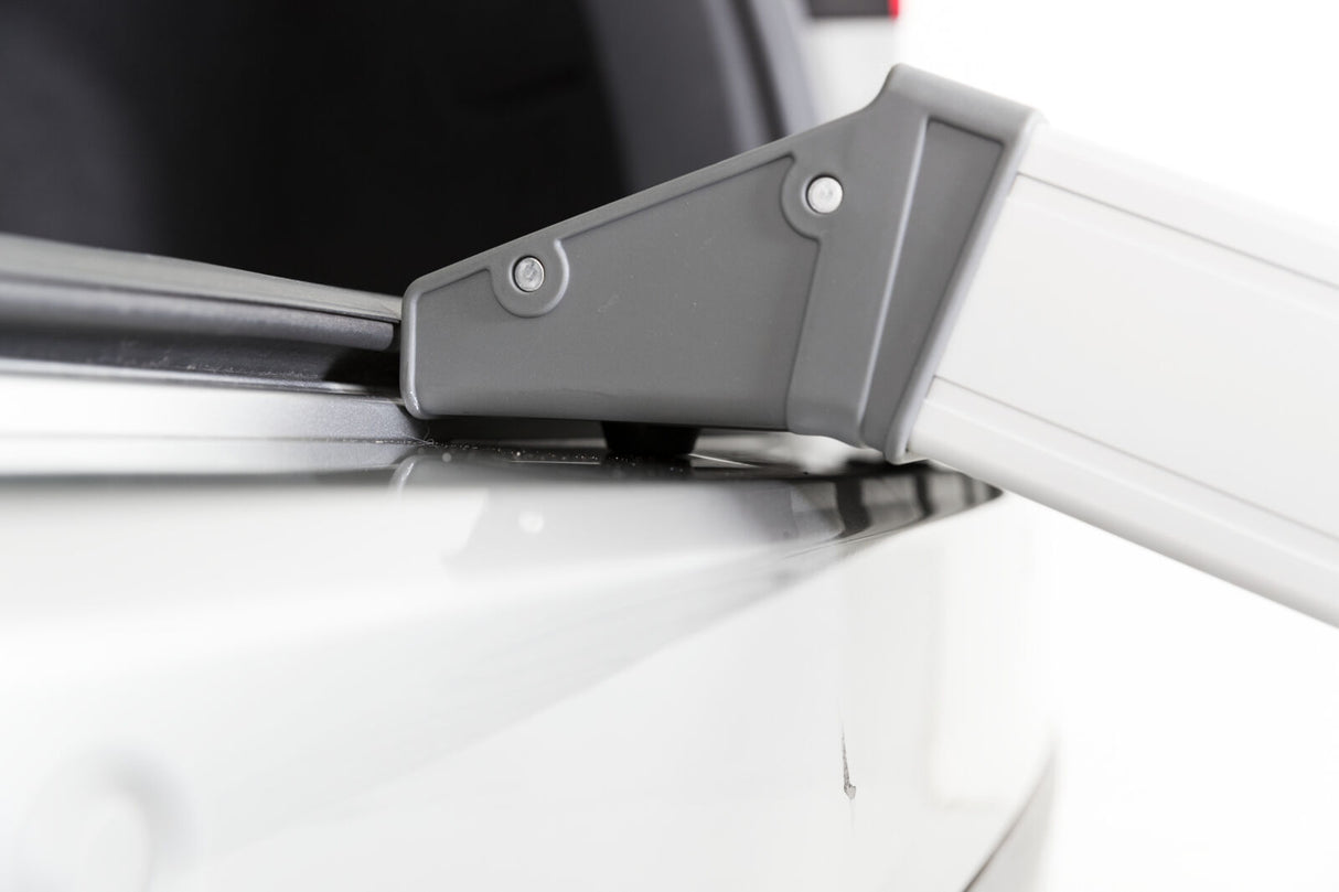 Graues Metallelement, befestigt an einem weißen, glänzenden Hintergrund, möglicherweise Teil einer Konstruktion oder eines Fahrzeugs.