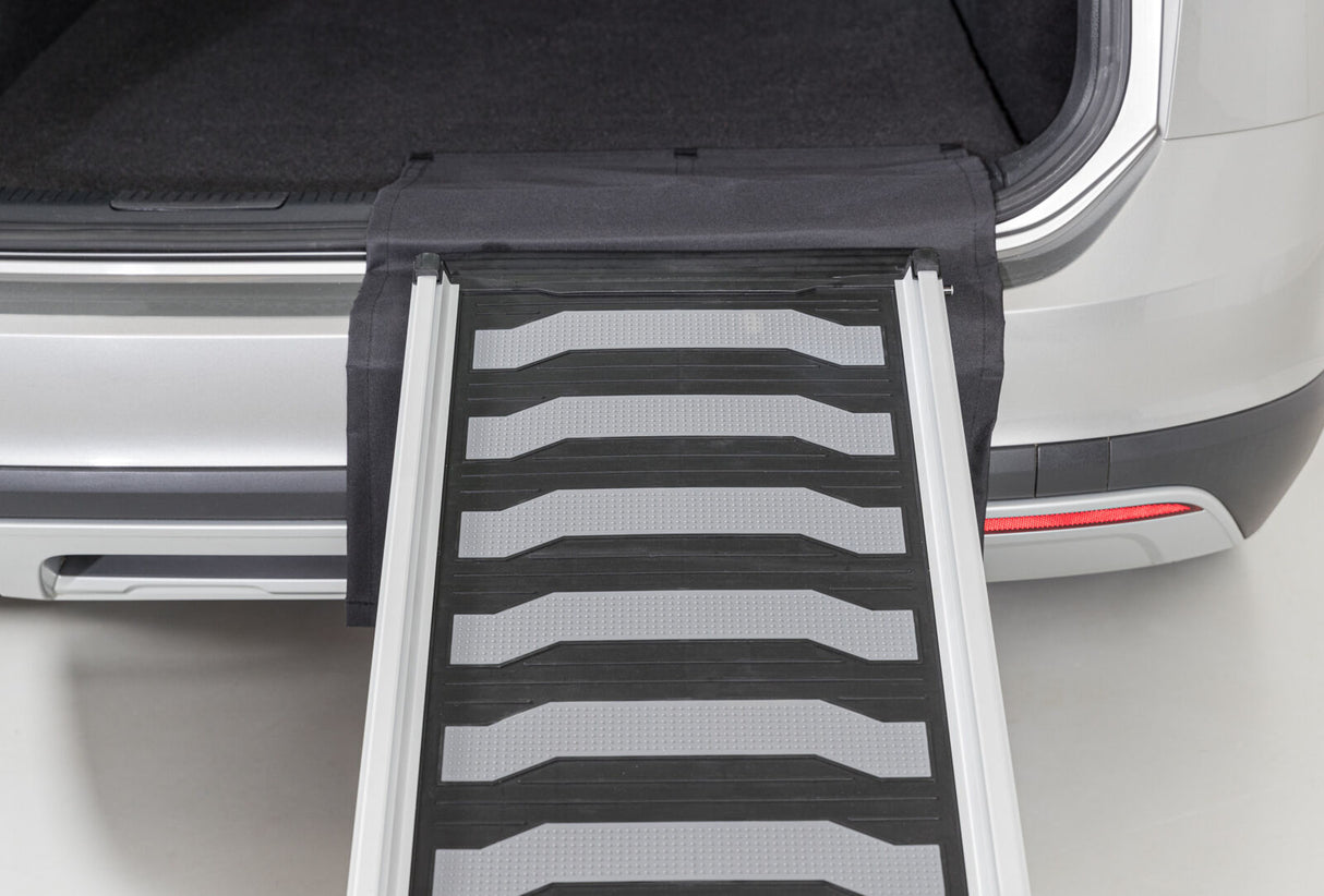 Metalle Rampe, die zu einem offenen Kofferraum eines silbernen Autos führt, mit schwarzen und grauen Details.