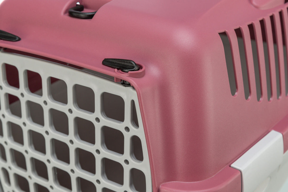Rosa Transportbox aus Kunststoff mit grauer Gittertür und schwarzen Verschlüssen.