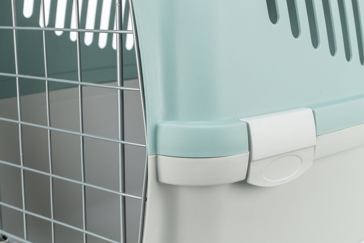 Nahaufnahme eines türkisfarbenen Transportkäfigs mit Metallgitter und weißem Verschluss.