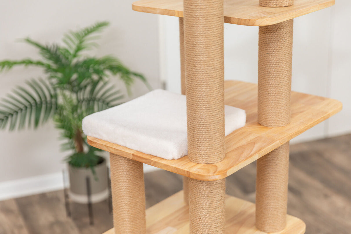 Kletterbaum mit Holzplattformen und Sisalumwickelten Säulen, weiße gepolsterte Fläche, hellbrauner Boden, Pflanze im Hintergrund.