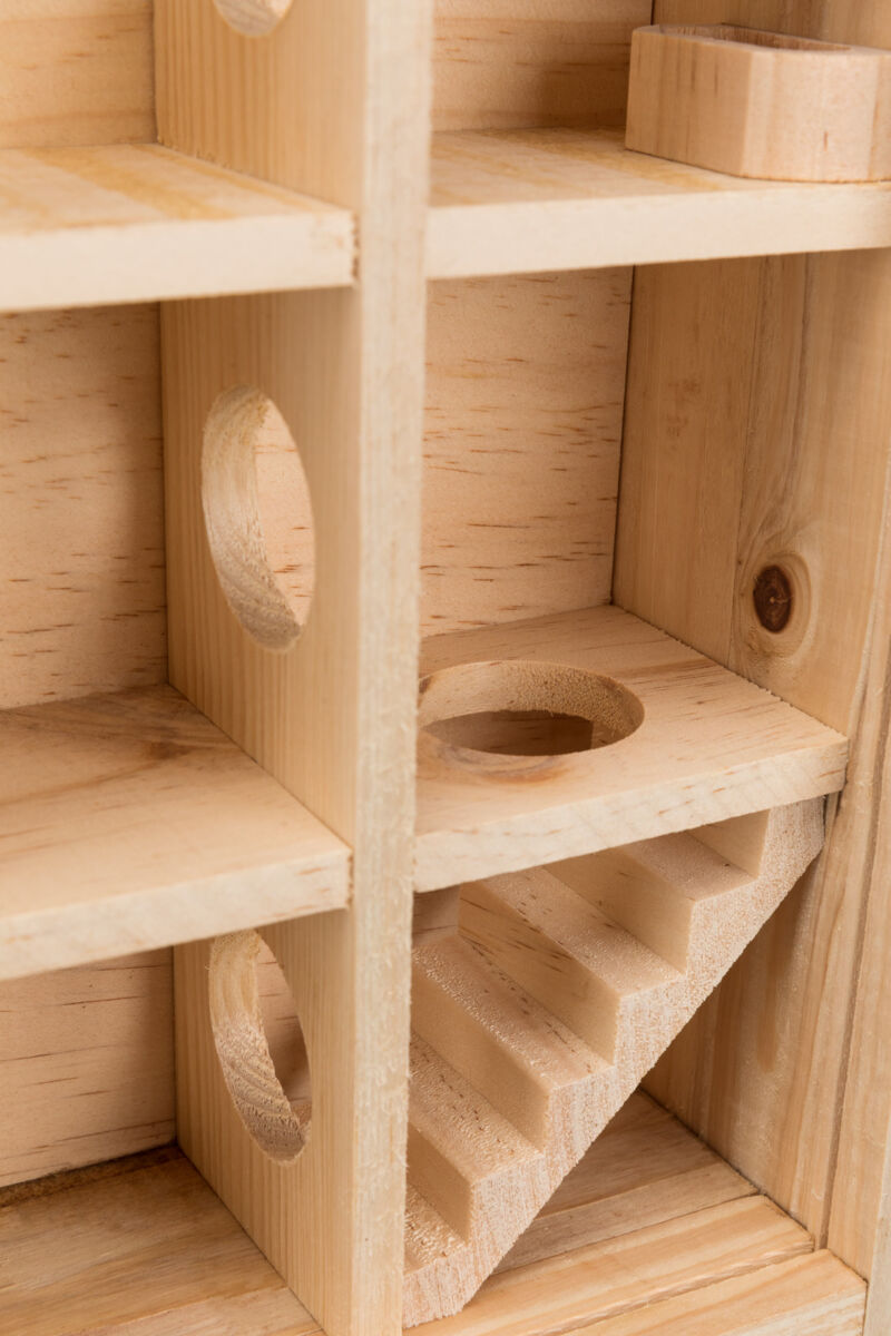 Holzstruktur mit gewinkelten Regalen, runden Öffnungen und einer kleinen Treppe in natürlicher Holzfarbe.