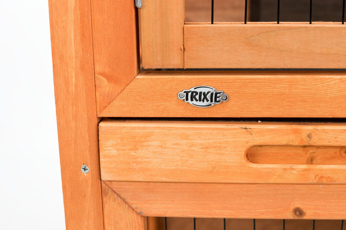Holzoberfläche mit Metallplakette, "TRIXIE" beschriftet, Schrauben und Details einer rechteckigen Struktur sichtbar.