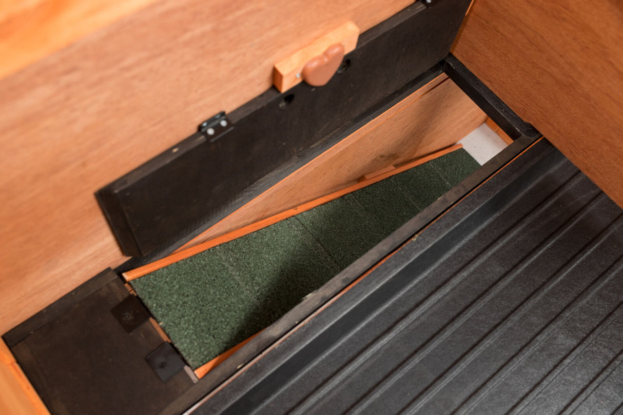 Holzkonstruktion mit schwarzem Rahmen und grünem Bodenbelag, teilweise geöffnet von oben fotografiert.