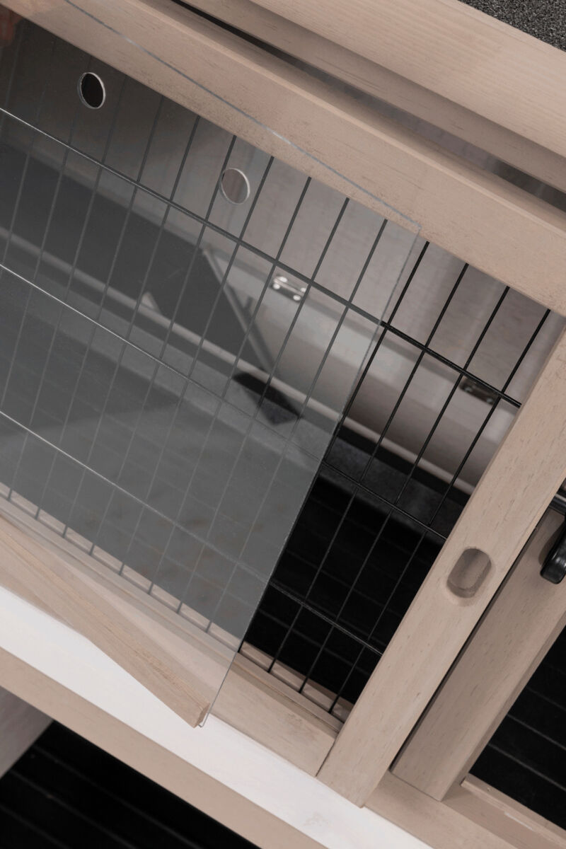 Durchsichtige Glasscheibe mit zwei Runden Ausschnitten, neben einem Holzelement mit schwarzem Gitter.