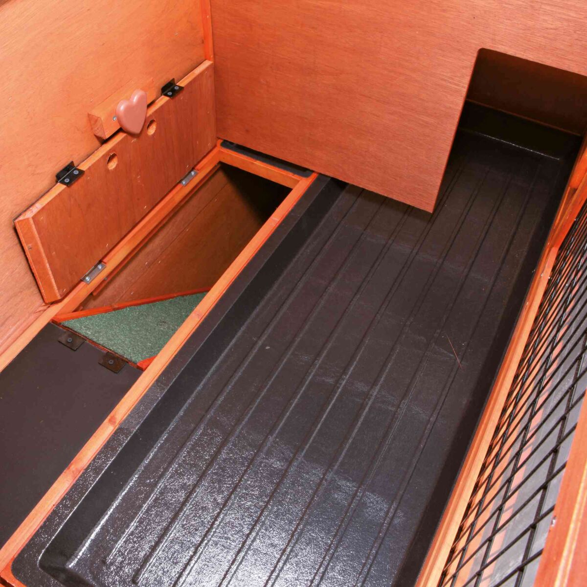 Holzbox mit herzförmigem Griff, seitlicher Einstieg und schwarzem, gerilltem Boden.