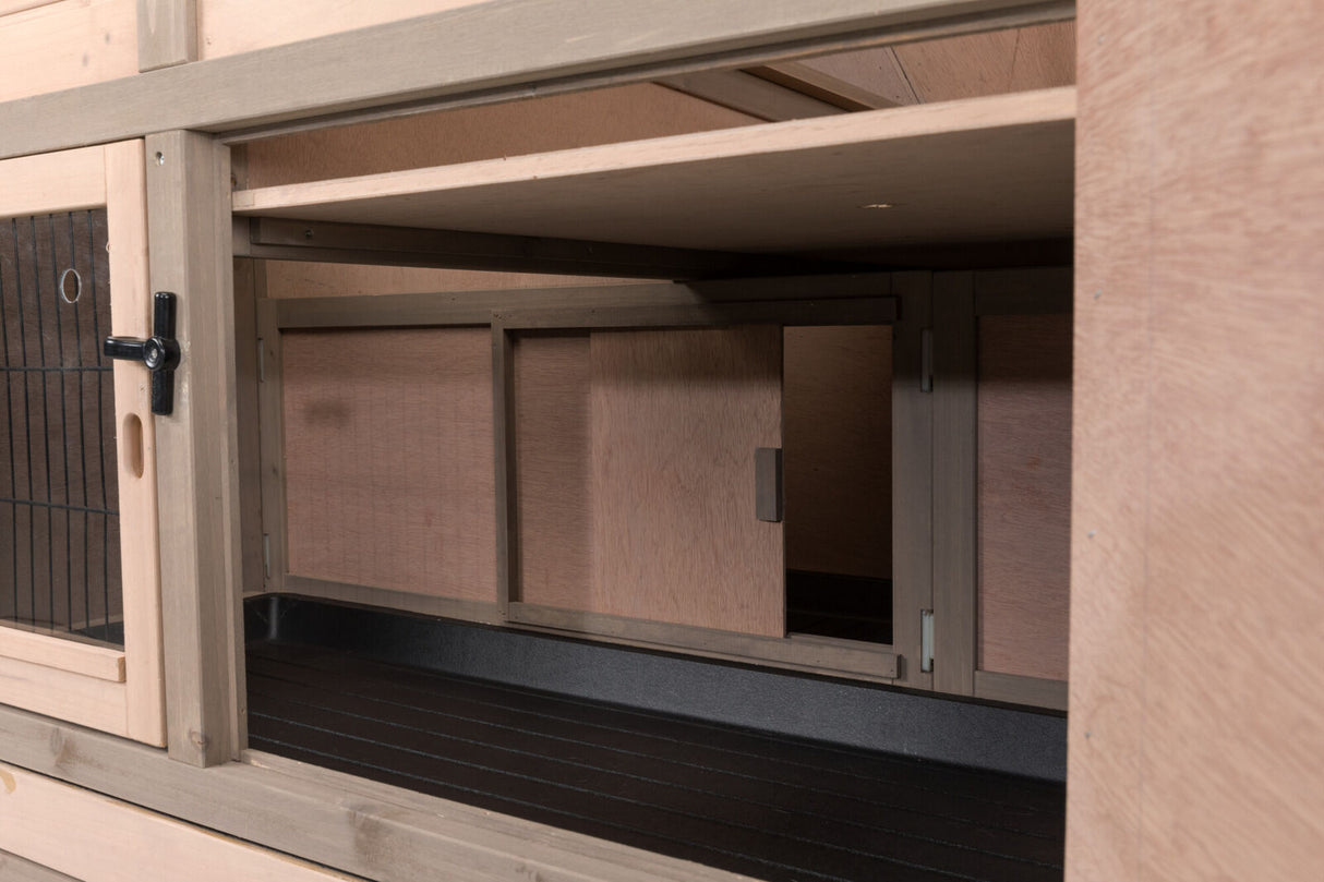 Holzgehege mit verschiebbarer Tür, innen Schwarz, Metallgitter links, Rahmen naturbelassen.