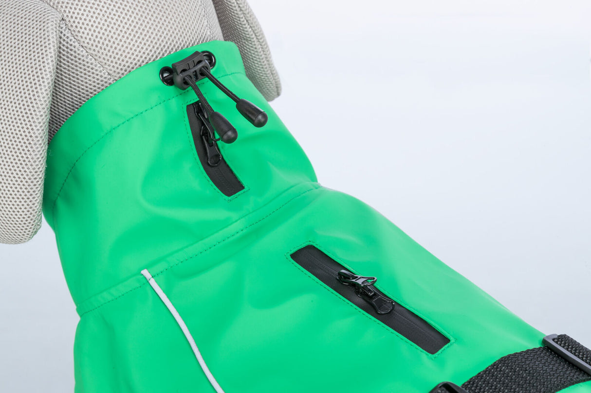 Grüner Hundemantel mit schwarzem Reißverschluss und Gummizug auf einem beigen Stoffmodell.