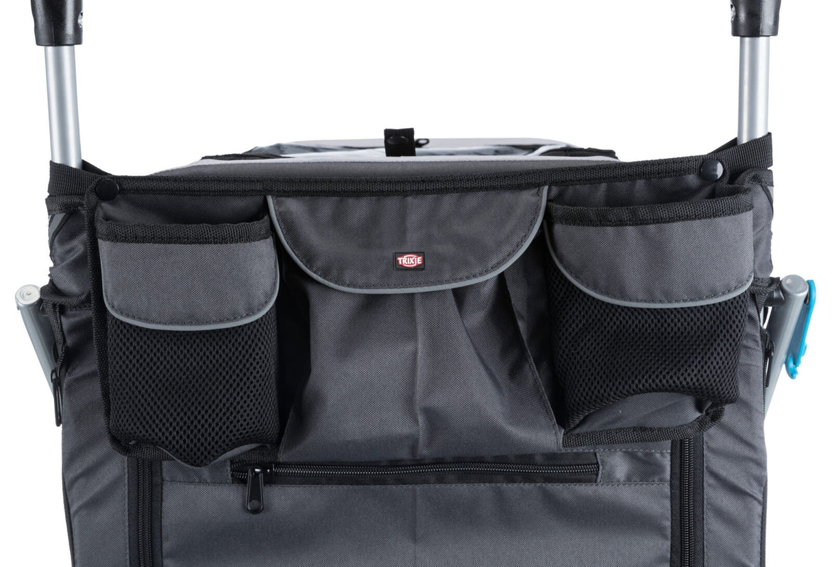 Grau-schwarzer Stoff mit mehreren Taschen und einem Reißverschluss auf einem fahrbaren Gestell.