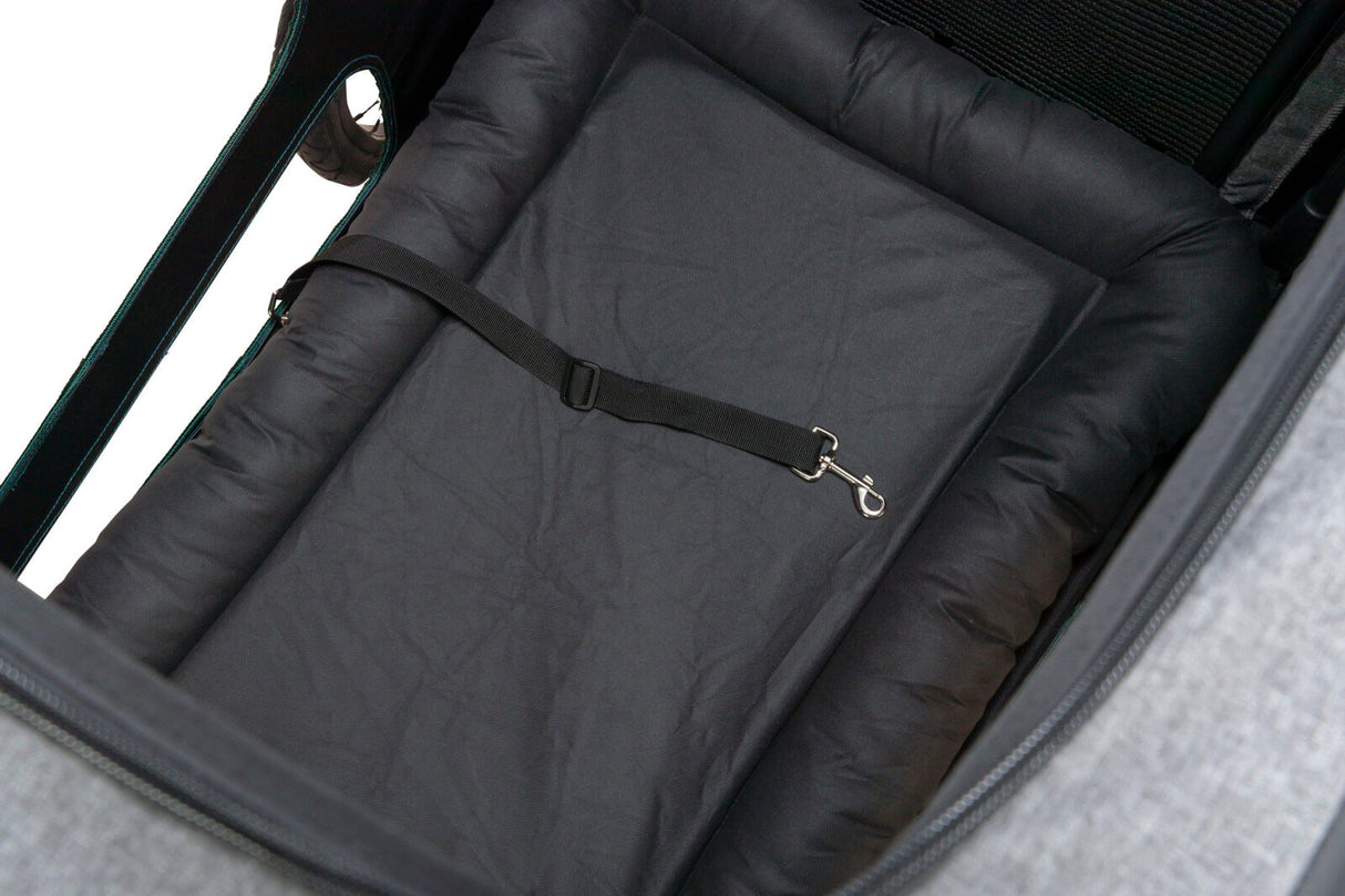 Innenansicht eines Fahrradanhängers mit schwarzer Polsterung und einem schwarzen Gurt mit silbernem Haken.