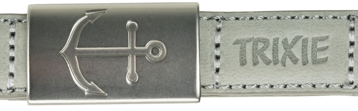 Silberne Metallschnalle mit eingraviertem Anker auf grauem Lederband, daneben der Schriftzug "TRIXIE".