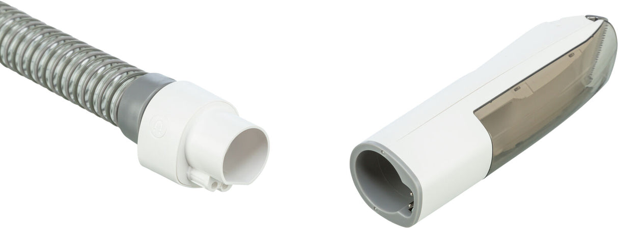 Graues, spiralförmiges Rohr mit weißem Anschlussstück links und weißem, länglichen Gehäuse mit grauer Öffnung rechts.