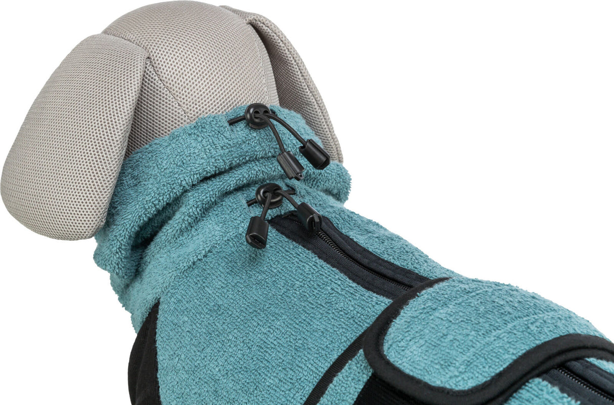 Ein Hundemantel in Türkis mit schwarzen Reißverschlüssen und Kordelzug auf einem Stoffmodell.