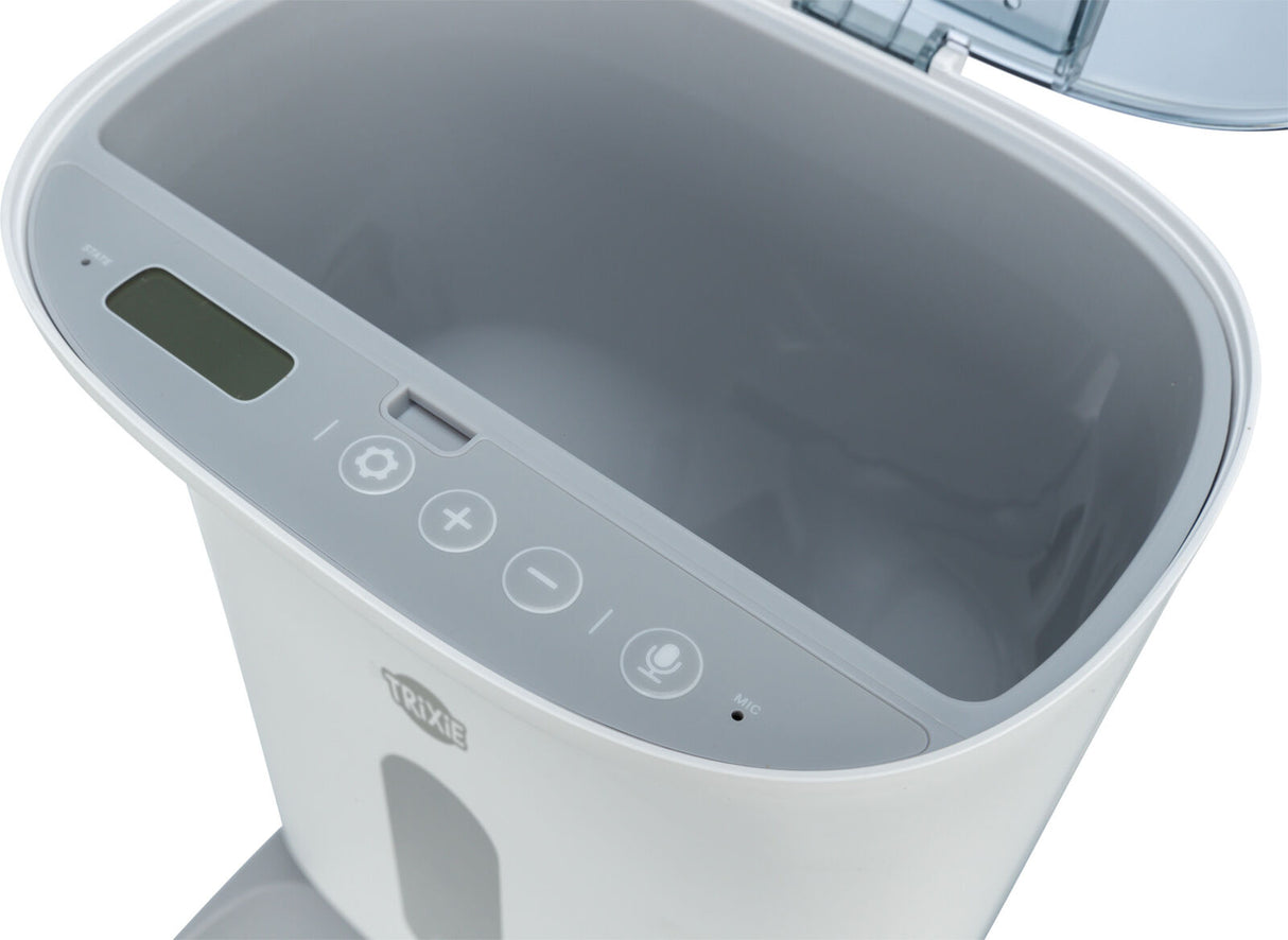 Weißer, ovaler Behälter mit digitalem Display und Tasten, ein transparentes, aufklappbares Fach oben.