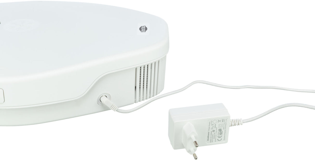 Ein weißes elektrisches Gerät mit Lüftungsschlitzen und einem angeschlossenen weißen Netzkabel.