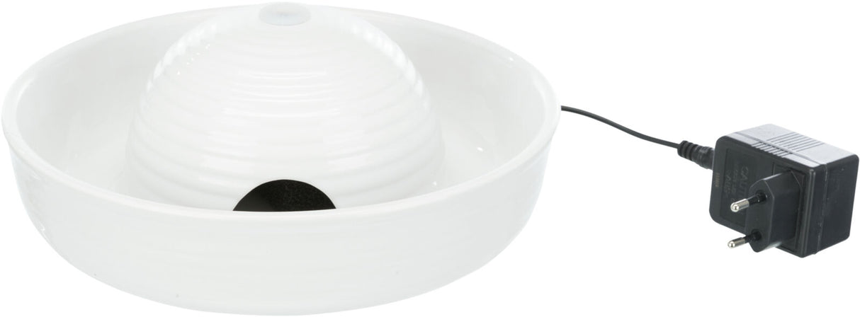 Weiße, runde Schale mit Kuppel und kleiner Öffnung, daneben ein schwarzes Netzteil mit Kabel.
