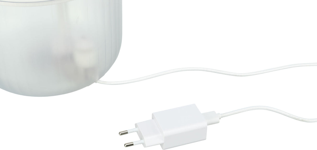 Ein weißes USB-Ladegerät mit angeschlossenem Kabel, das in ein halbtransparentes, zylindrisches Gefäß führt.