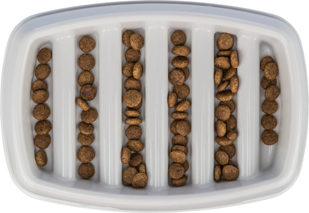 Braune Trockenfutterstückchen liegen in Reihen auf einem weißen Tablett mit vertikalen Rillen.