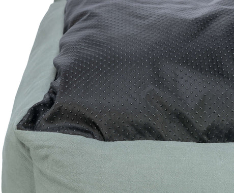 Grau-grünes Kissen mit schwarzer, genoppter Oberfläche.