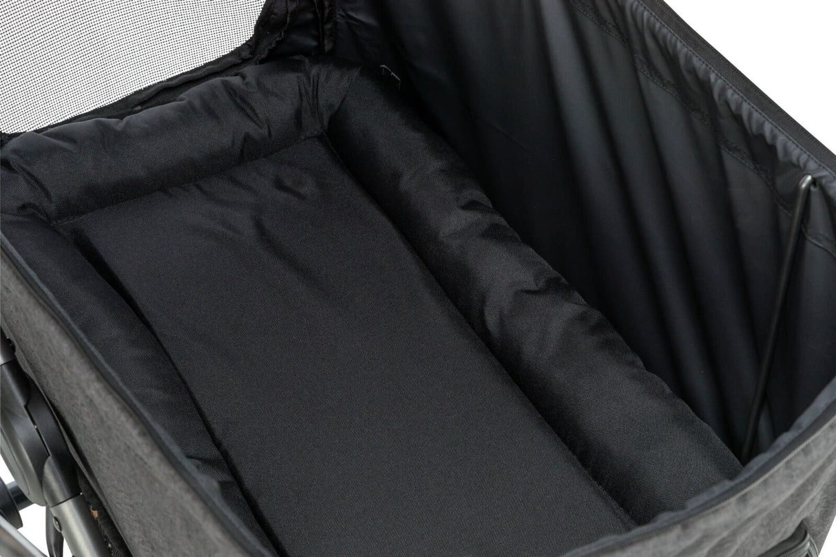 Innenansicht eines schwarzen, gepolsterten Fahrradanhängers mit Netzgewebe oben und stabiler Umrandung.