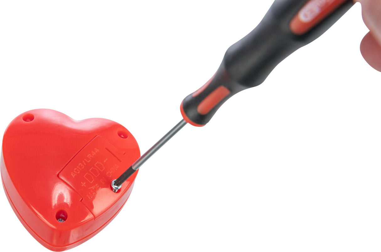Roter herzförmiger Gegenstand mit Schraubendreck beim Öffnen des Batteriefachs, sichtbarer Text: AG13/LR44, Made in China.