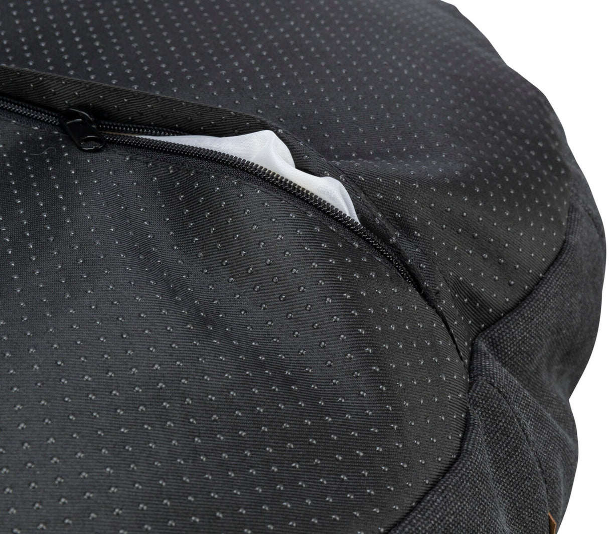 Schwarzer Stoff mit kleinen, weißen Punkten und einem teilweise geöffneten Reißverschluss, darunter weißer Stoff sichtbar.