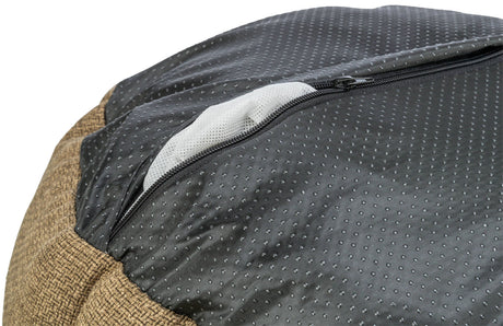 Nahaufnahme eines Kissens mit brauner Textur und schwarzem, gepunktetem Stoff sowie einem Reißverschluss.