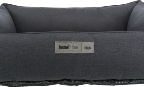 Ein dunkelgraues rechteckiges Bett mit einem Etikett mit der Aufschrift "homeEdition TRIXIE" auf der Vorderseite.