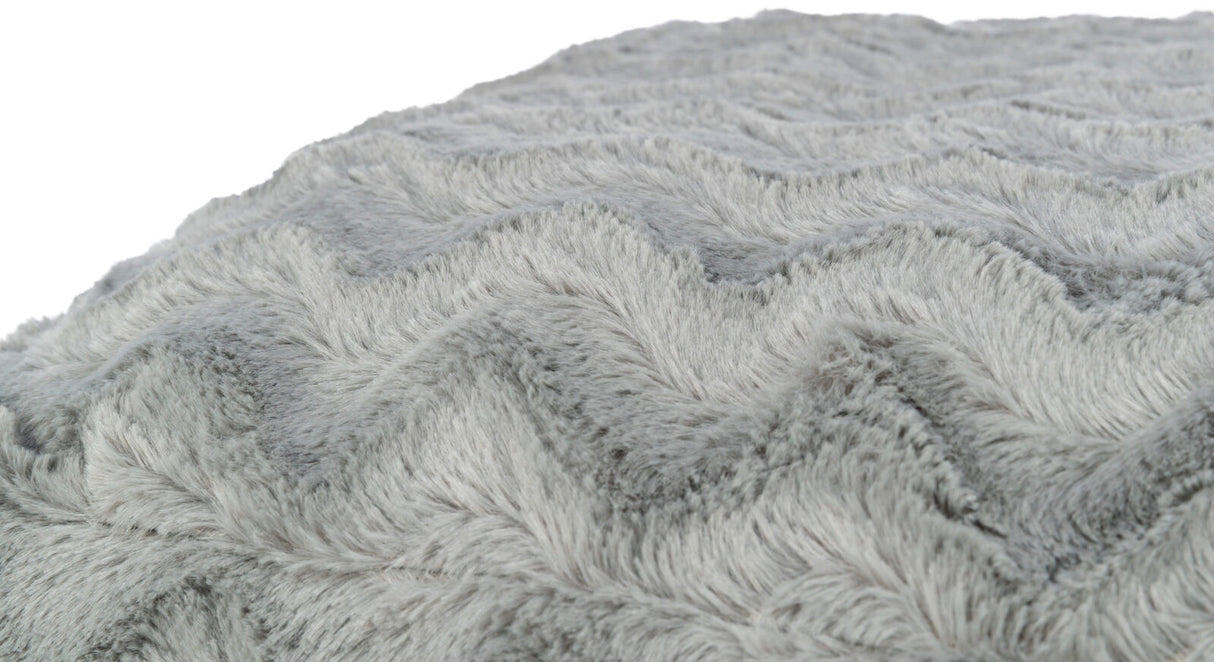Graue flauschige Oberfläche mit einem wellenförmigen Muster in Nahaufnahme, weich und strukturiert sichtbar.