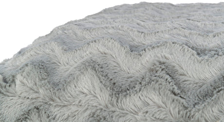 Graue flauschige Oberfläche mit einem wellenförmigen Muster in Nahaufnahme, weich und strukturiert sichtbar.