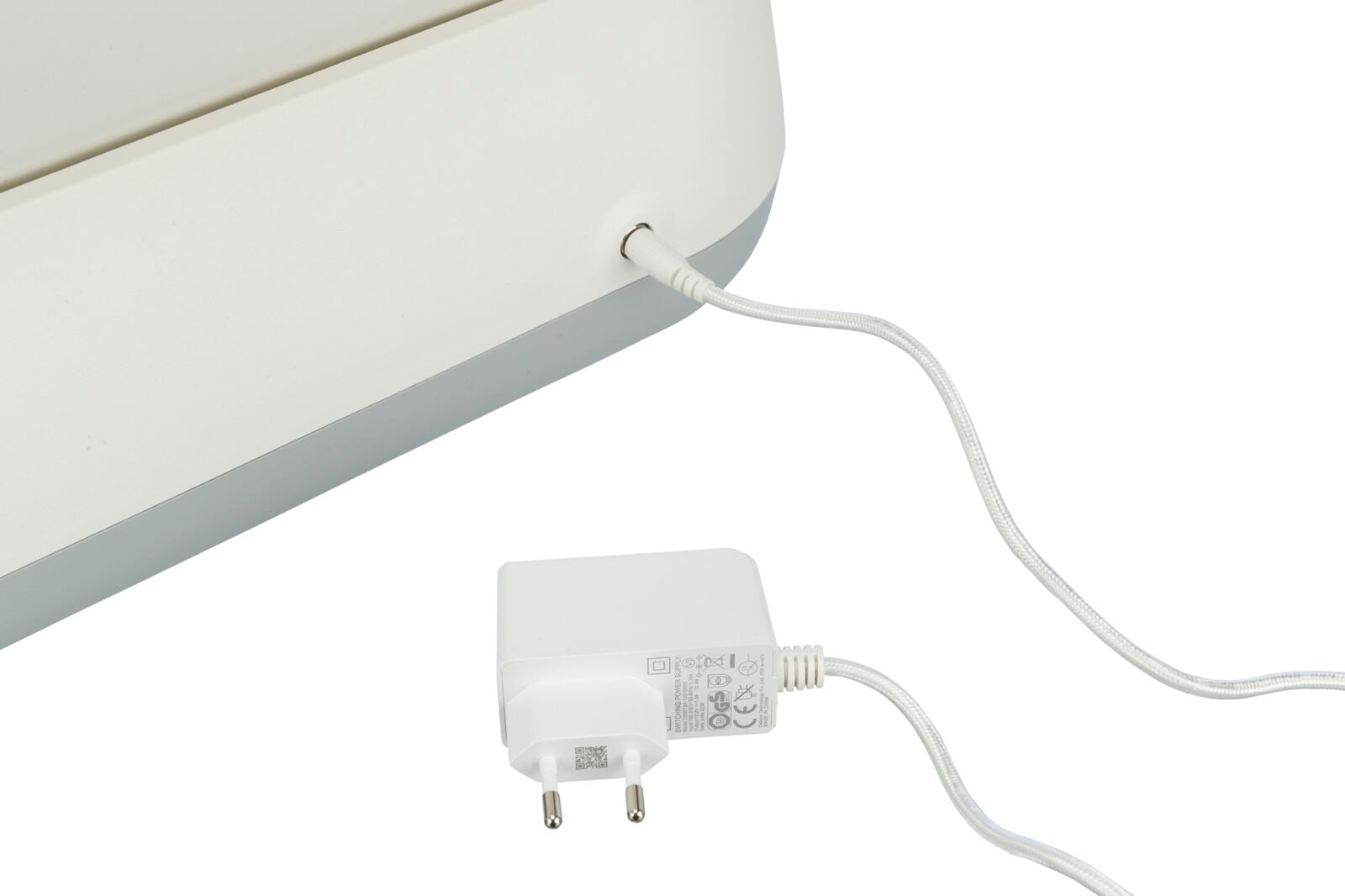 Ein weißes Ladegerät ist mit einem weißen elektrischen Gerät verbunden, das teilweise sichtbar ist.