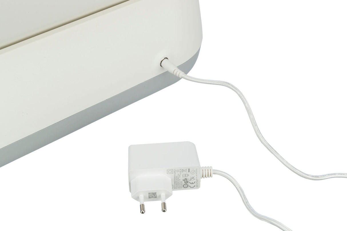 Ein weißes Ladegerät ist mit einem weißen elektrischen Gerät verbunden, das teilweise sichtbar ist.