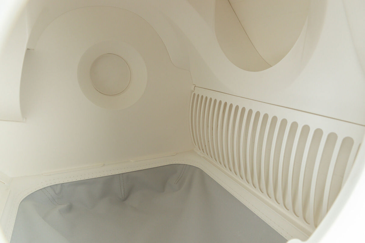 Innenansicht einer hellen, glattwandigen Struktur mit kreisförmigen und gerillten Elementen, darunter ein grauer Einsatz.