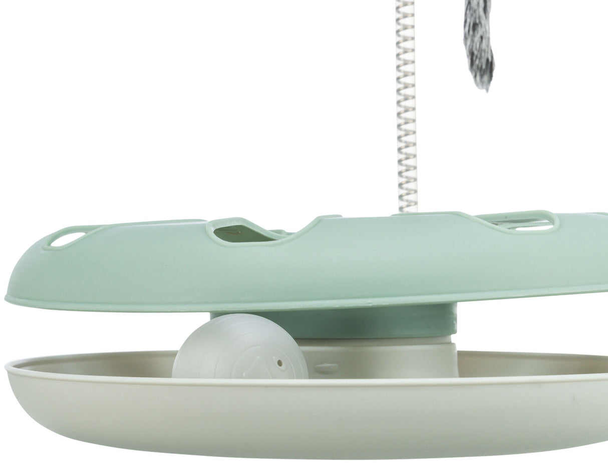 Kreisspielzeug mit grünem Deckel, darunter Kugel in beige Schale, mit senkrechter Feder und Spielanhang.