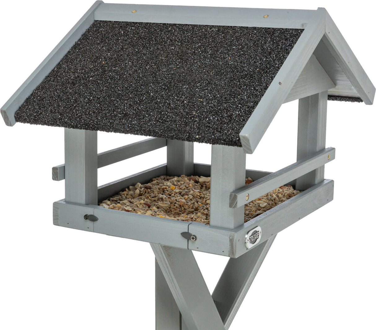Graues hölzernes Vogelhaus mit schwarzem Dachbelag, gefüllt mit gemischtem Vogelfutter auf einem breiten Sockel.
