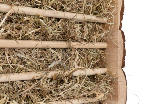 Heu zwischen mehreren horizontalen Holzstäben in einer halbkreisförmigen Holzstruktur.