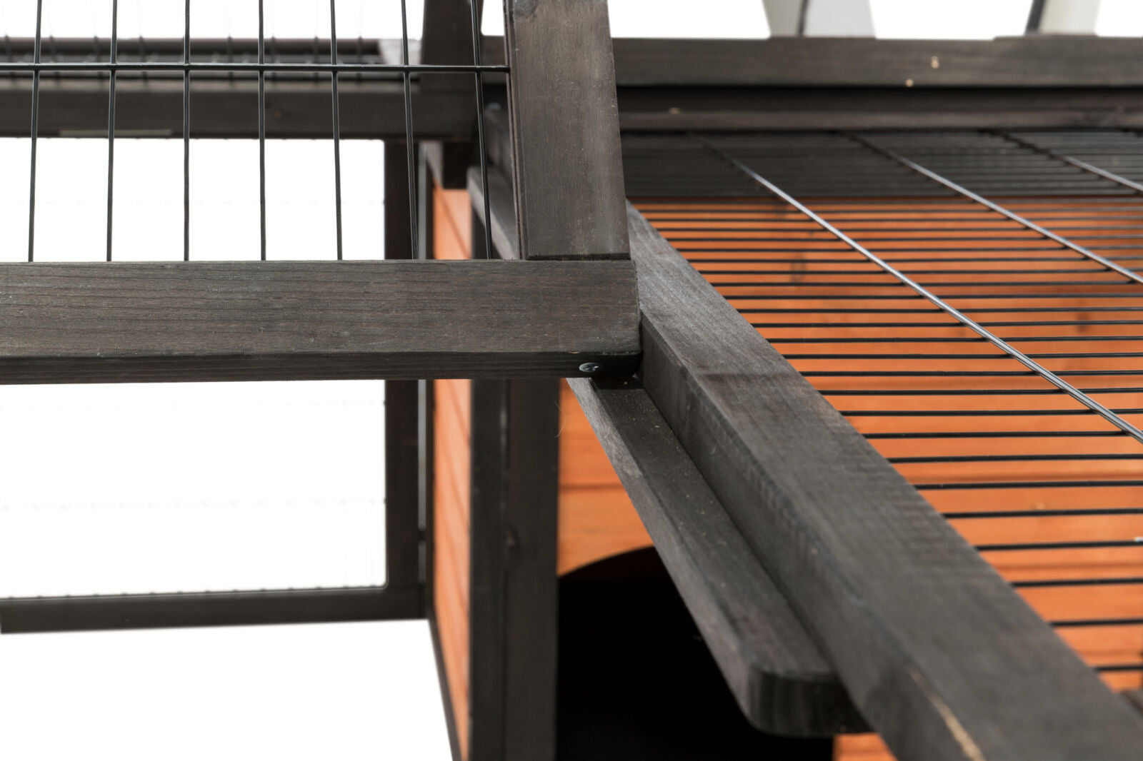 Schwarzes Metallgitter und Holzkonstruktion mit orangefarbener Paneel, Perspektive von unten nach oben.