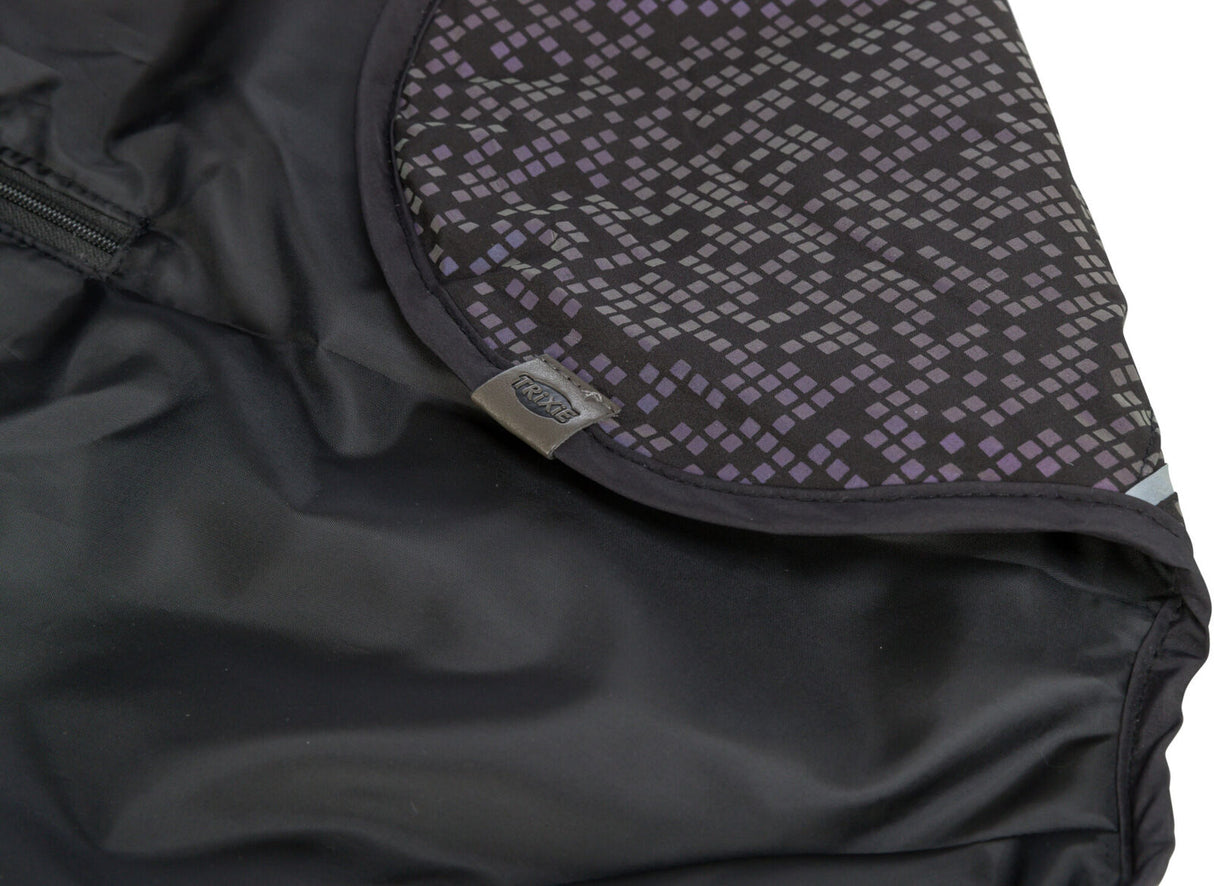 Schwarzer Stoff mit geometrischem Muster in Lila und Grau, Label mit "TRIXIE"-Schriftzug sichtbar.
