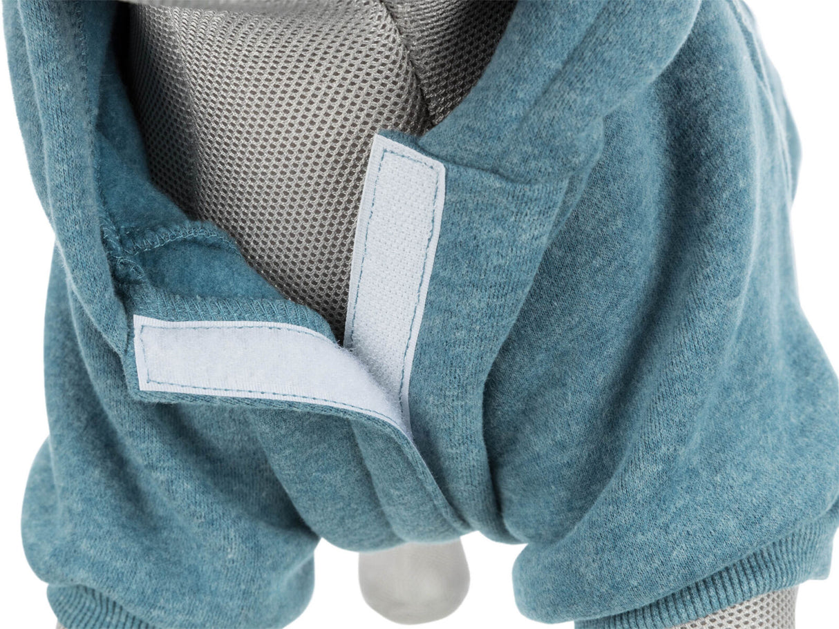 Grauer Stoff über einem Objekt mit sichtbarem, blauem Kleidungsstück und Klettverschluss.