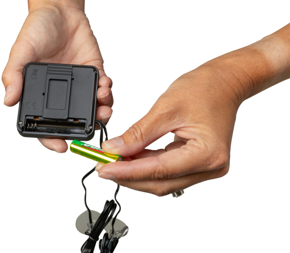 Eine Hand hält ein schwarzes Batteriefach, während eine zweite Hand eine gelb-grüne Batterie einsetzt.