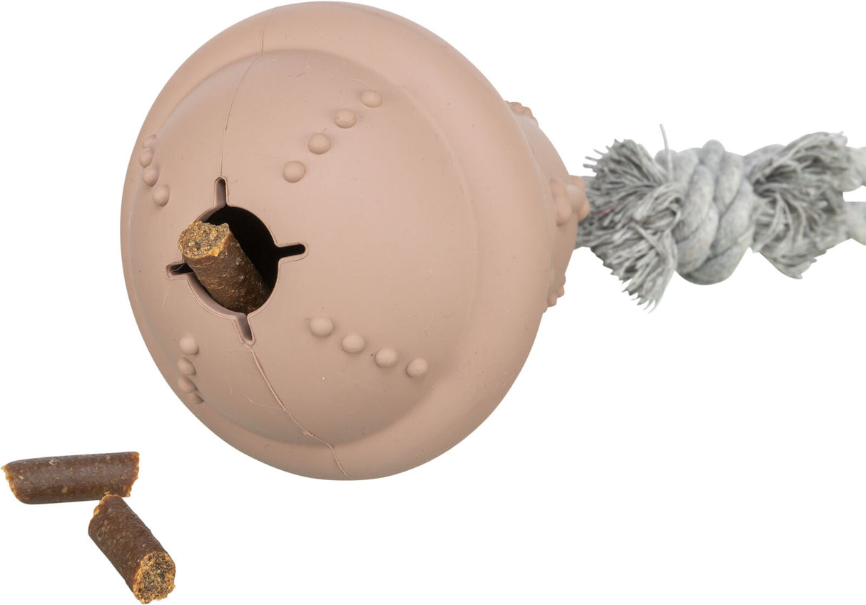 Beiges Hundespielzeug in Kugelform mit strukturierten Oberflächen und Seil, gefüllt mit braunem Futterstab.