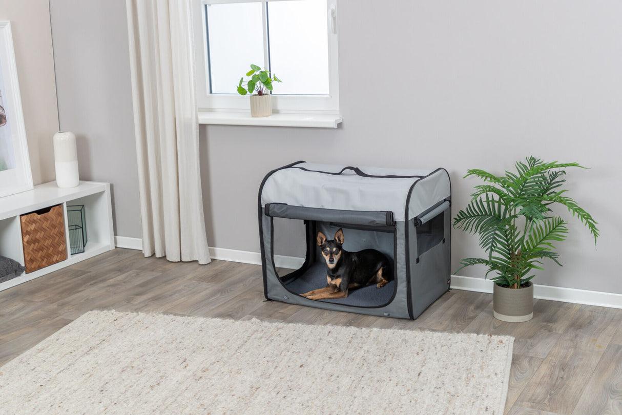 Grauer Hundekäfig im Wohnzimmer mit kleinem Hund darin, umgeben von Pflanzen und moderner Einrichtung.