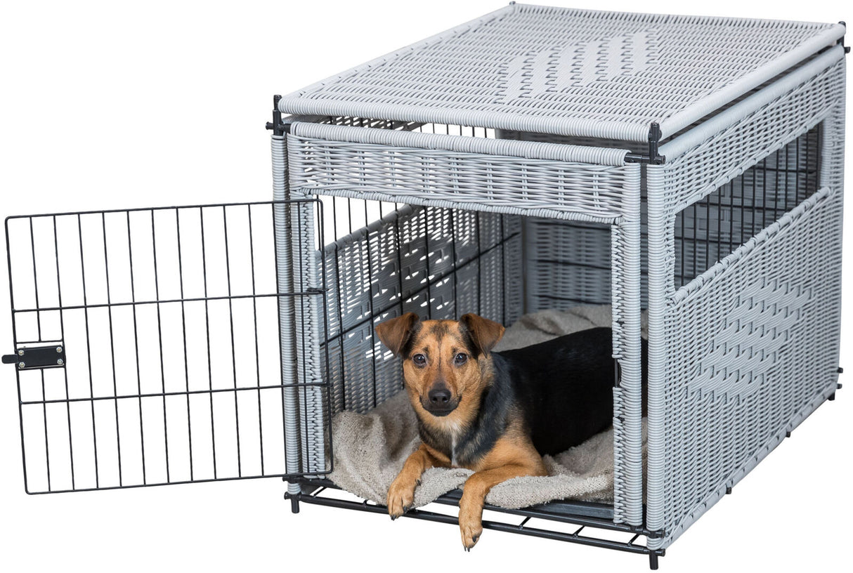 Ein kleiner Hund liegt auf einer hellen Decke in einem offenen, grauen Gitterkäfig mit geflochtenem Muster.