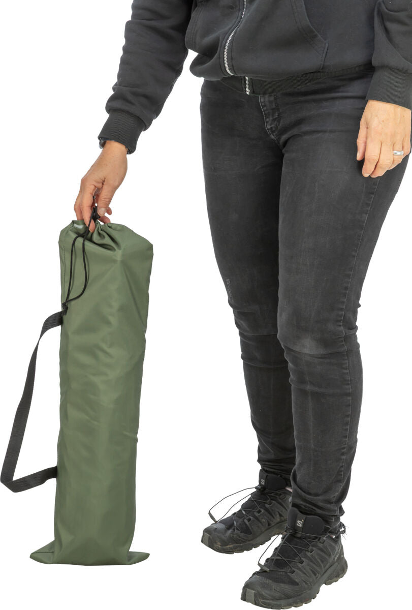Person in schwarzer Kleidung hält eine grüne Tasche mit schwarzem Riemen in der Hand.