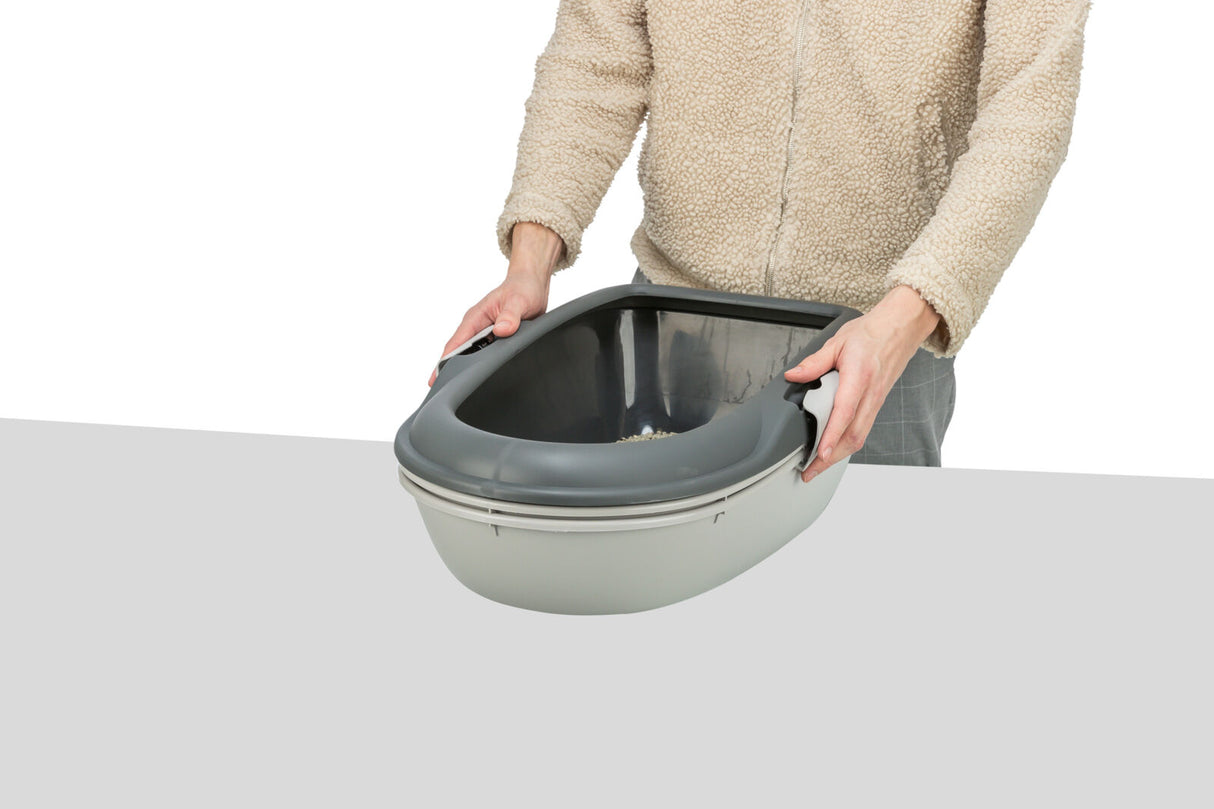 Eine Person hält eine graue und weiße Katzentoilette ohne Haube auf einem Tisch.