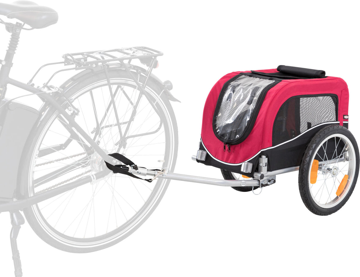 Ein roter Fahrradanhänger mit schwarzen und durchsichtigen Elementen ist an einem Fahrrad befestigt, die Reifen haben orange Reflektoren.